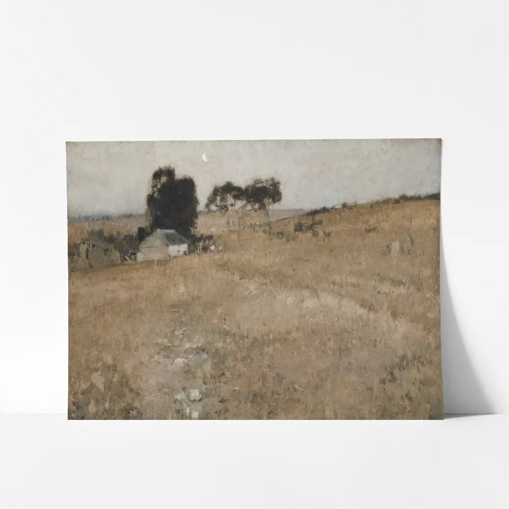 A mockup view of a vintage printable wall art featuring a serene rural landscape with a weathered cottage nestled in a field of golden grass. 